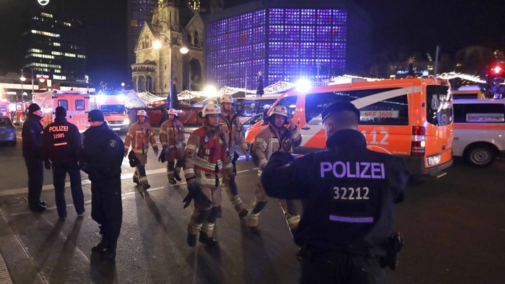 Firefighters walk past ambulances after a truck ran into a crowded Christmas market and killed several people in Berlin on December 19, 2016.