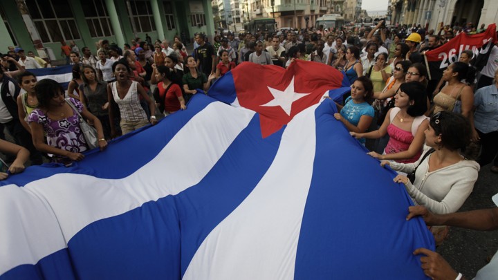 Pro-government youth carry a Cuban flag in front of the Ladies in White during a protest march in Havana on March 25, 2010.