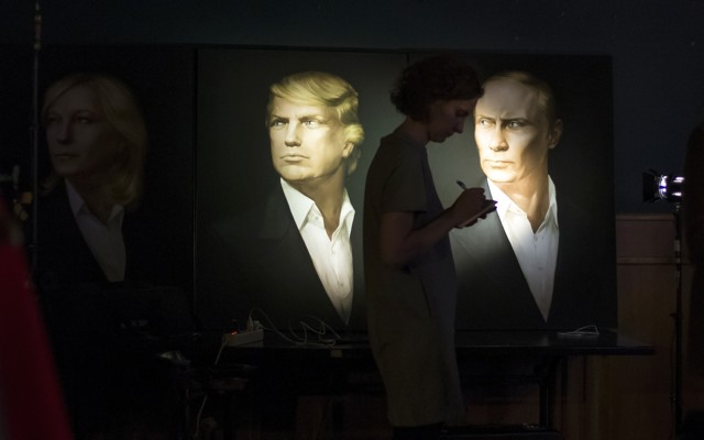 A journalist writes as she watches a telecast of the U.S. presidential election standing at portraits of U.S. presidential candidate Donald Trump and Russian President Vladimir Putin in the Union Jack pub in Moscow, Russia on Nov. 9, 2016.