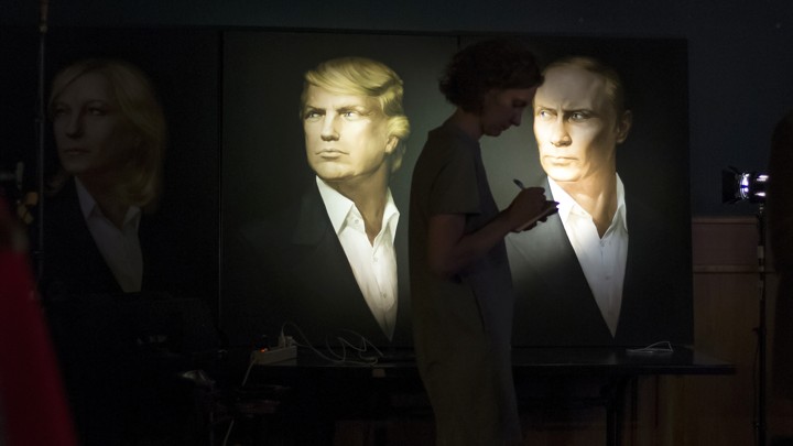 A journalist writes as she watches a telecast of the U.S. presidential election standing at portraits of U.S. presidential candidate Donald Trump and Russian President Vladimir Putin in the Union Jack pub in Moscow, Russia on Nov. 9, 2016.
