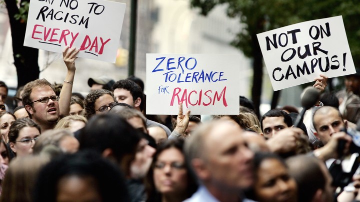 People hold signs reading "say no to racism every day," "zero tolerance for racism," and "not on our campus!"