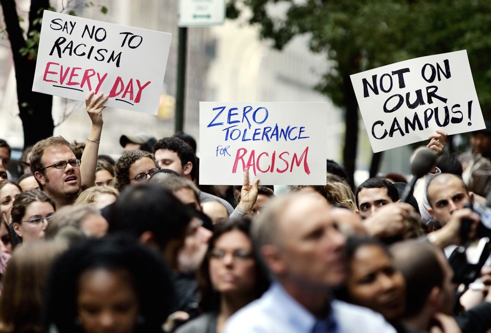 People hold signs reading "say no to racism every day," "zero tolerance for racism," and "not on our campus!"