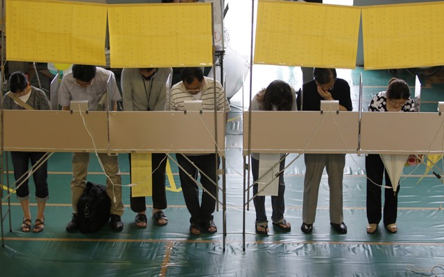 Voters fill out ballots for Japan's upper house election at a polling station in Tokyo on July 11, 2010.