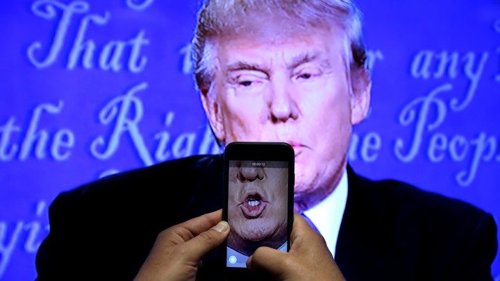 A journalist records a video from screen as Republican U.S. presidential nominee Donald Trump speaks during the first presidential debate with U.S. Democratic presidential candidate Hillary Clinton at Hofstra University.