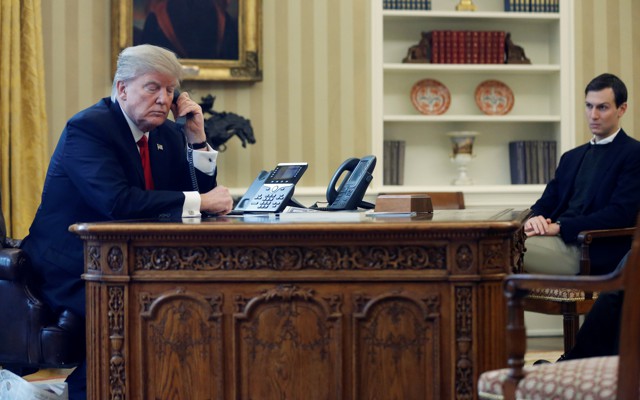 Donald Trump speaks on the phone as Jared Kushner looks on.