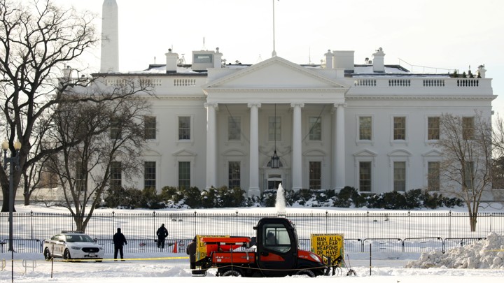 A worker drives a snow plow to clear the sidewalk in front of the White House in January of last year.