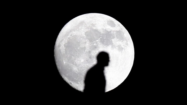 The silhouette of a man in front of the moon