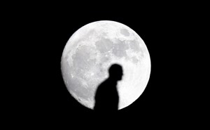 The silhouette of a man in front of the moon