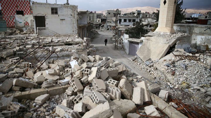 A man walks past damaged buildings in the rebel-held besieged city of Douma.