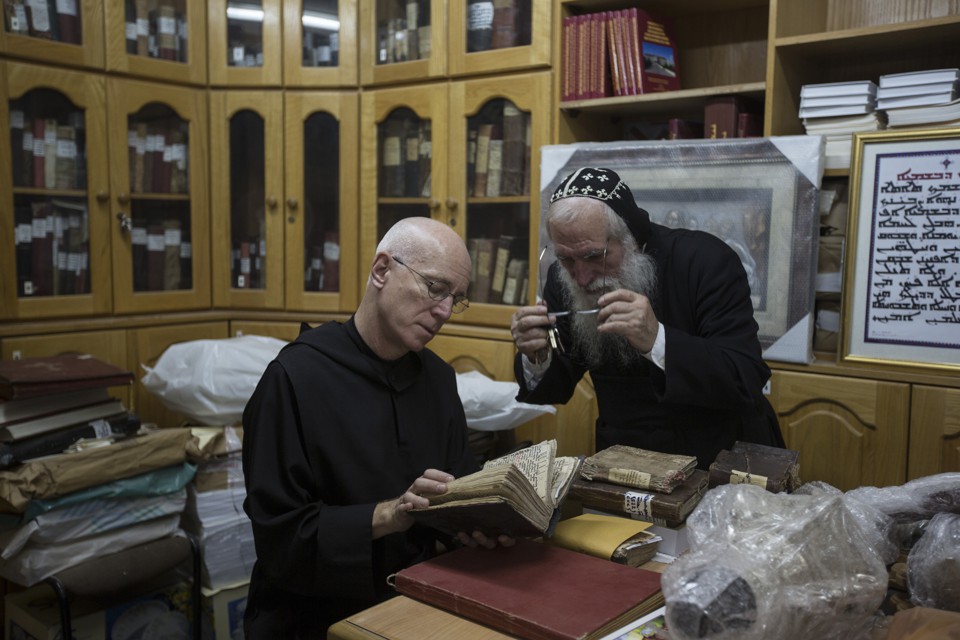 Father Columba Stewart inspects an ancient manuscript as a Syriac monk looks on at St. Mark’s Syrian Orthodox Monastery in Jerusalem.