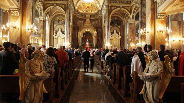 The inside of a Basilica filled with ornate and religious arches, paintings, and statues