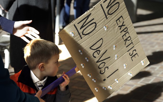 A 3-year-old boy carries a sign opposing Betsy DeVos`
