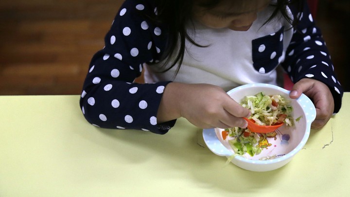 A child eats a bowl of salad.