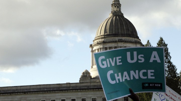 Someone holds a sign reading "give us a chance"