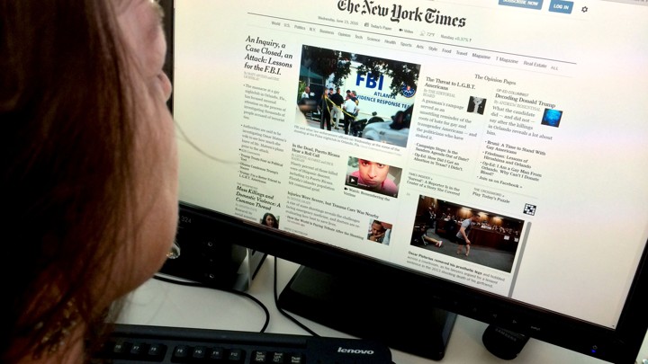 A woman reads The New York Times on her computer