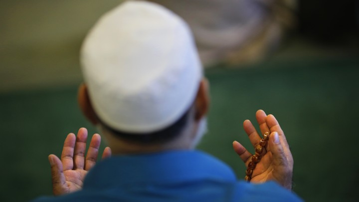 A man holds his hands out in prayer.