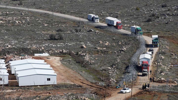 Trucks removing pre-fabricated homes drive along a road leading out of the recently evicted Israeli settler outpost of Amona.