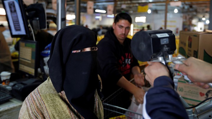 A Syrian refugee has her eyes scanned by a device to verify her identity so that she can receive her foodstuff at a refugee camp, in Mafraq, Jordan.