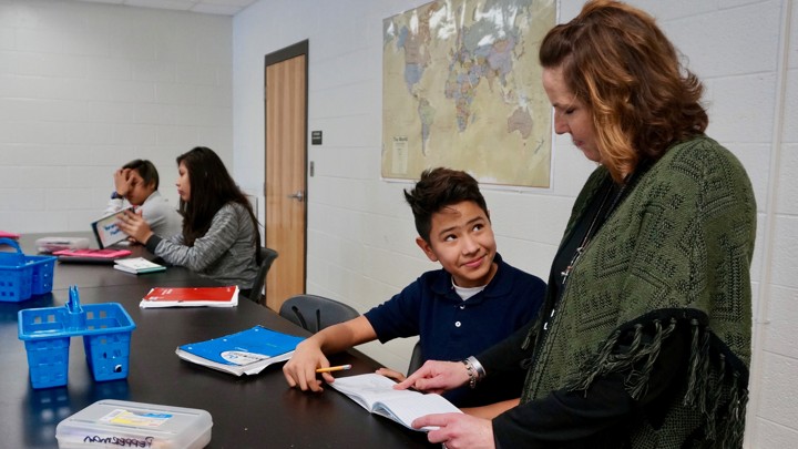 An adult and student look at a worksheet together.