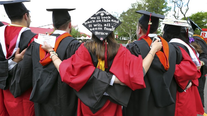 Graduates embrace in caps and gowns at commencement