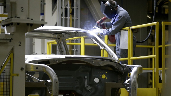 An auto worker works on a car.