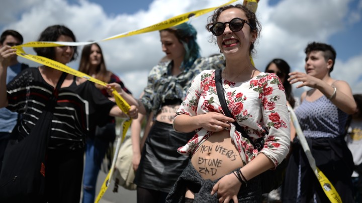 A woman shows writing reading 'my uterus is a ZAD (zone to defend)' as protesters face supporters of the anti-gay marriage La Manif Pour Tous (Protest for Everyone) movement during a protest against medically assisted procreation techniques for lesbian couples and surrogacy on May 10, 2016 in Nantes, western France.
