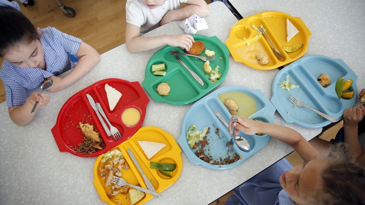 An overhead shot of students sitting with colorful lunch trays at a cafeteria table