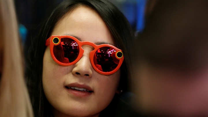 A woman wears bright red Snapchat Spectacles, glasses made by the popular app, on the floor of the New York Stock Exchange, on March 2, 2017.