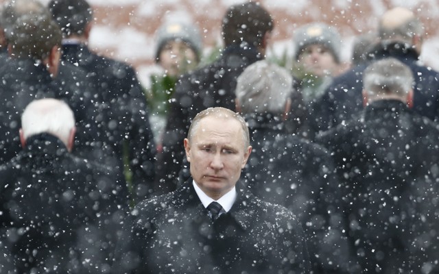 Russian President Vladimir Putin stands in the snow at a wreath laying ceremony.