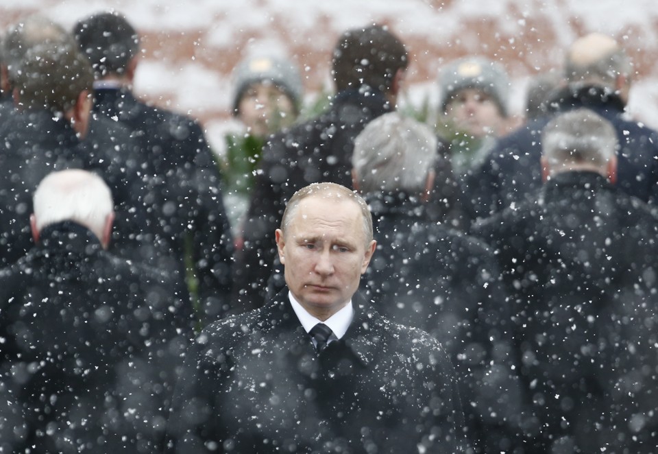 Russian President Vladimir Putin stands in the snow at a wreath laying ceremony.