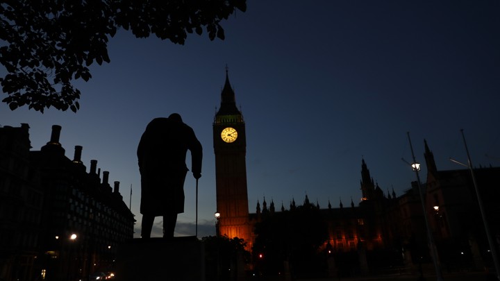 Dawn breaks behind the Houses of Parliament and the statue of Winston Churchill in Westminster, London, on June 24, 2016.