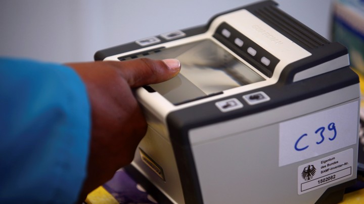 A woman places her thumb on a fingerprint scanner.