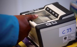 A woman places her thumb on a fingerprint scanner.