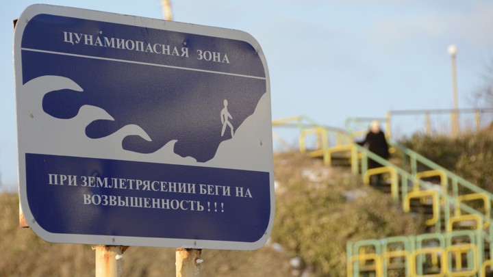 A blue tsunami warning sign on a beach