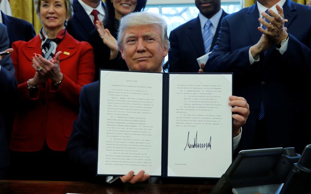 President Donald Trump holds a signed copy of an executive order