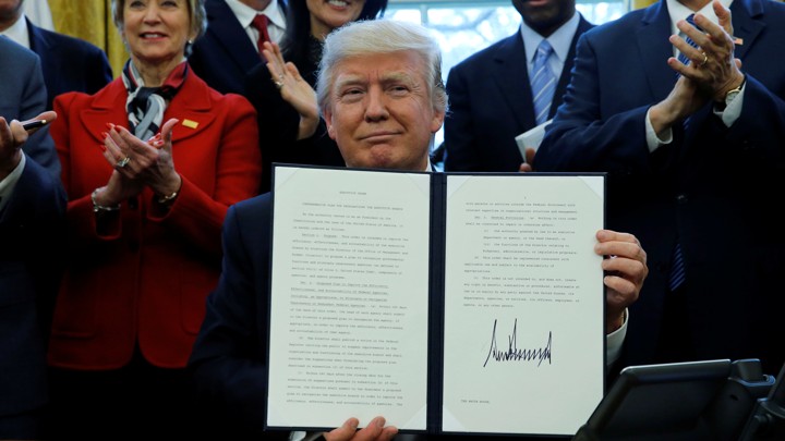 President Donald Trump holds a signed copy of an executive order