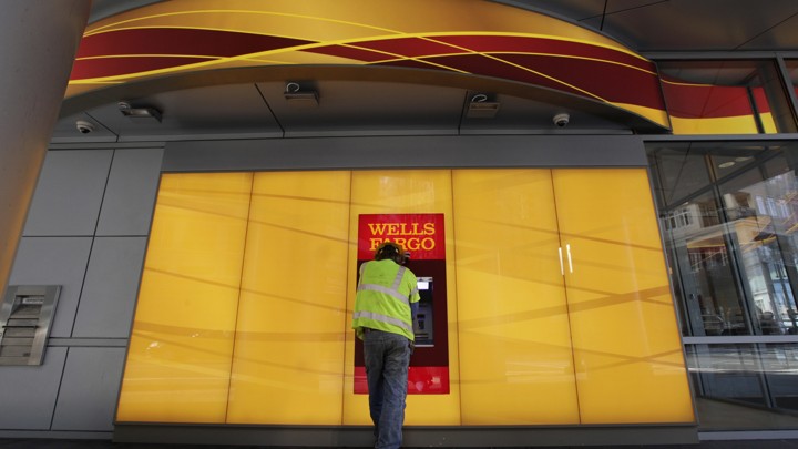 A man stands at a Wells Fargo ATM.
