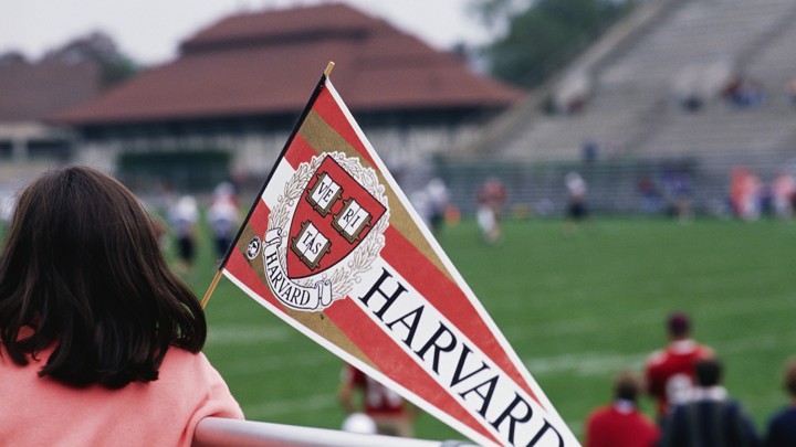 A girl holds a Harvard pennant.