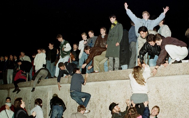 East German citizens climb the Berlin wall at the Brandenburg Gate as they celebrate the opening of the East German border on November 10, 1989.