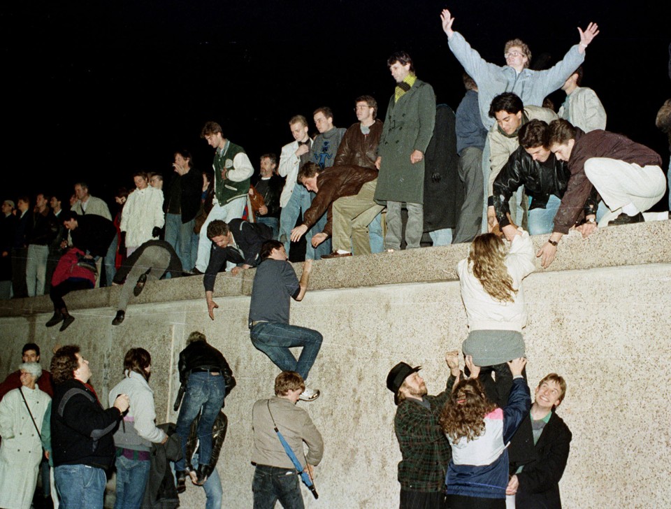 East German citizens climb the Berlin wall at the Brandenburg Gate as they celebrate the opening of the East German border on November 10, 1989.