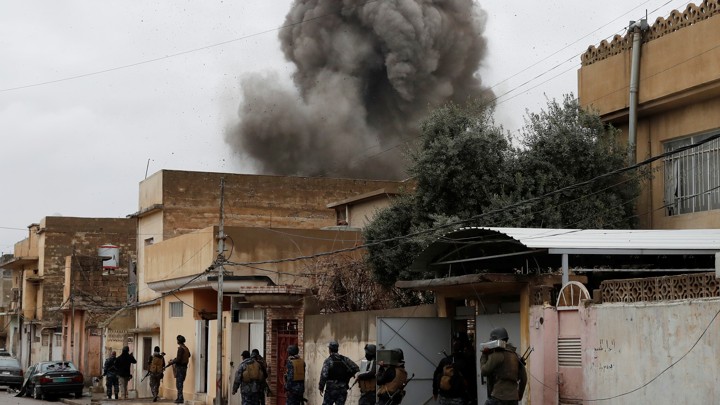 Iraqi policemen walk during an airstrike against Islamic State militants in Mosul, Iraq, on March 4, 2017.