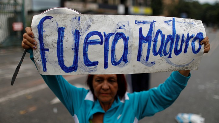 An opposition supporter holds a placard that reads "Maduro out" as she attends a rally against Venezuela.