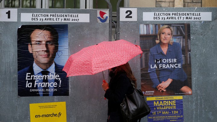 A woman walks past posters of presidential candidates Emmanuel Macron and Marine Le Pen in Paris, France on April 28, 2017.