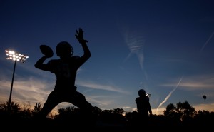 A silhouette of a high-school football player throwing a pass