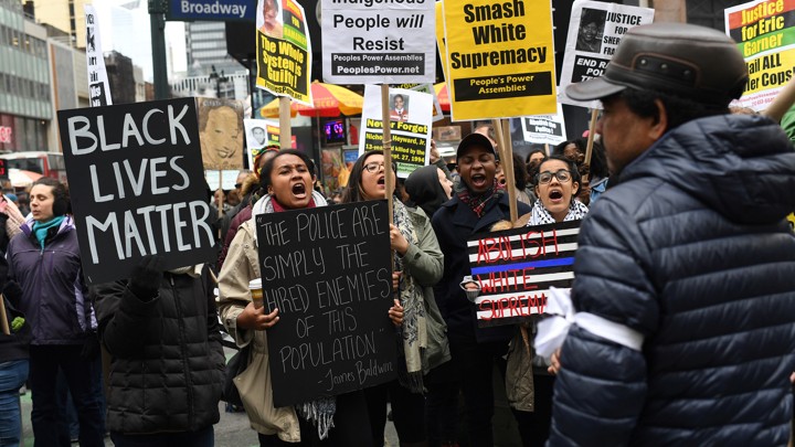 Black Lives Matter activists hold signs reading, "Black lives matter," "smash white supremacy," and "brown and indigenous people will resist."
