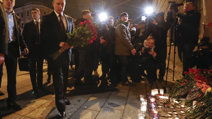 Russian president Vladimir Putin puts flowers down outside Tekhnologicheskiy Institut metro station in St. Petersburg, Russia.