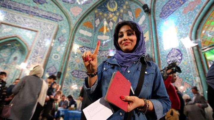 An Iranian woman shows her inked finger after casting her ballot at a polling station in Tehran on February 26, 2016.