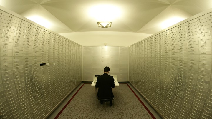 An employee sits amongst safe boxes in a safe room at a Swiss bank