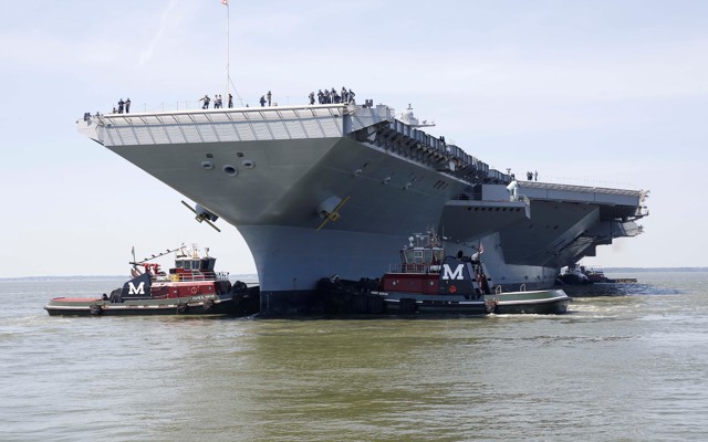 The Gerald R. Ford is maneuvered by tug boats in the James River