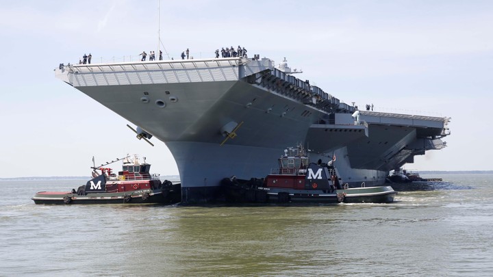 The Gerald R. Ford is maneuvered by tug boats in the James River